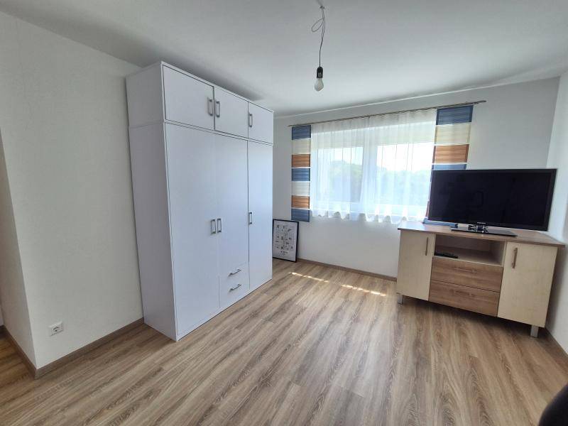 Helles Zimmer mit Kleiderschrank, Holzboden und großem Fenster.