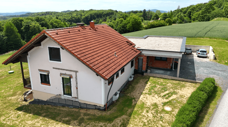 Rückansicht des Hauses mit Gartenbereich und angrenzendem Anbau, umgeben von viel Grün.