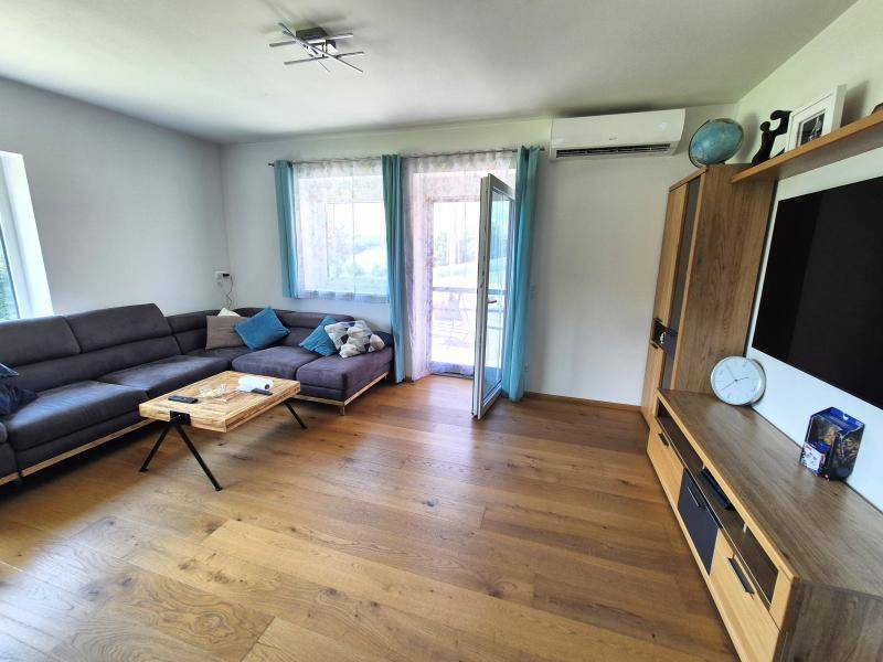 Modern eingerichtetes Wohnzimmer mit bequemer Couch, Holzboden und Klimaanlage.