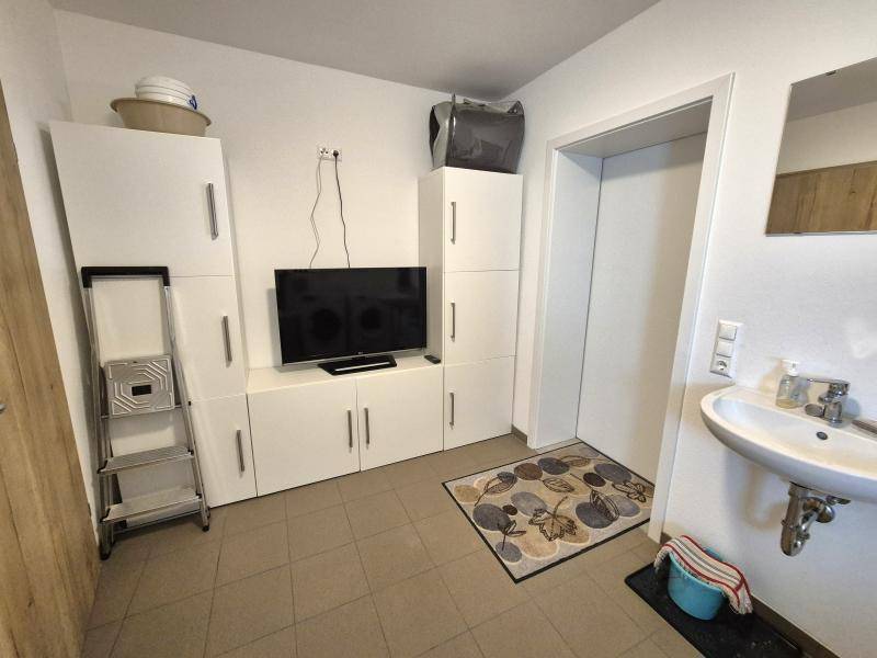 Multifunktionaler Raum mit Stauraum, Fernseher und einem kleinen Waschbecken, ideal für verschiedene Zwecke.