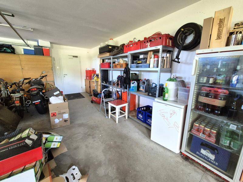 Große Garage mit umfangreichen Regalsystemen, Kühlschrank und viel Stauraum für Werkzeuge und Vorräte.