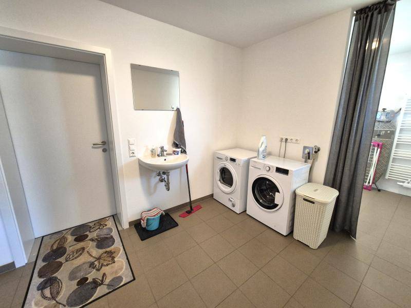 Praktischer Hauswirtschaftsraum mit Waschmaschinen, Waschbecken und ausreichend Platz für Wäschepflege.