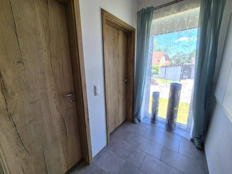 Heller Flur mit Fliesenboden, Holztüren und großem Fenster.