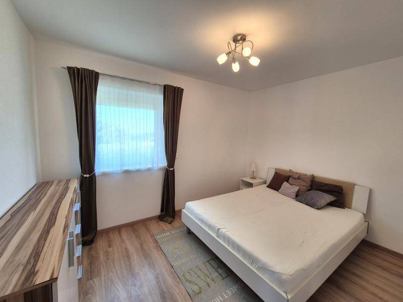 Gemütliches Schlafzimmer mit Doppelbett, Holzboden und Fenster mit Vorhängen.