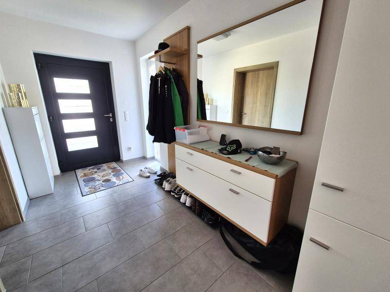 Eingangsbereich mit Fliesenboden, Garderobe und großem Spiegel.