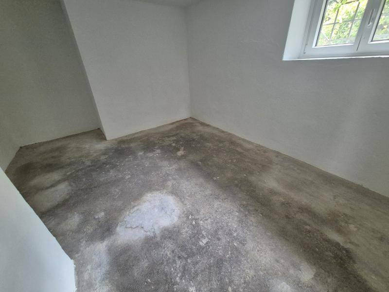 Heller, leerer Raum mit Betonboden und einem Fenster, ideal für Lagerung oder Hobbyzwecke.