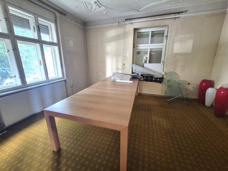 Geräumiges Zimmer mit großem Holztisch, Teppichboden und zwei Fenstern.