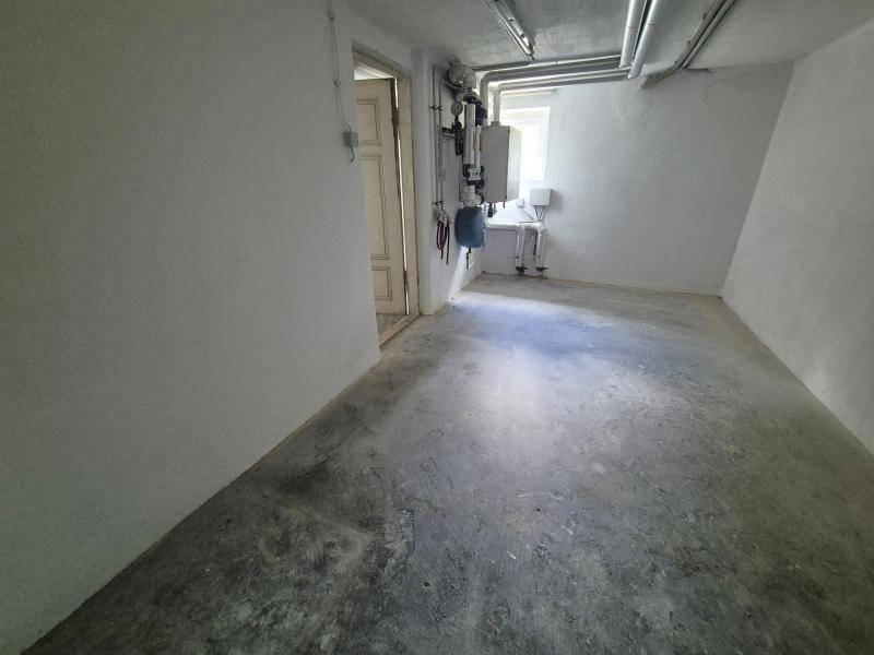 Kellerraum mit Heizungsanlage, Rohren und Betonboden, als Technikraum genutzt.