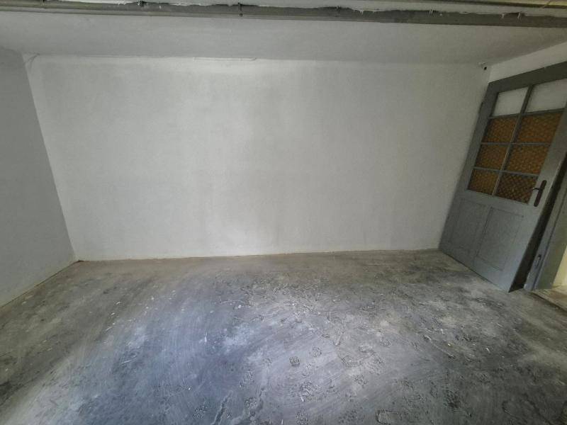 Leerer Kellerraum mit Betonboden und einer Tür, ideal als Abstellraum.