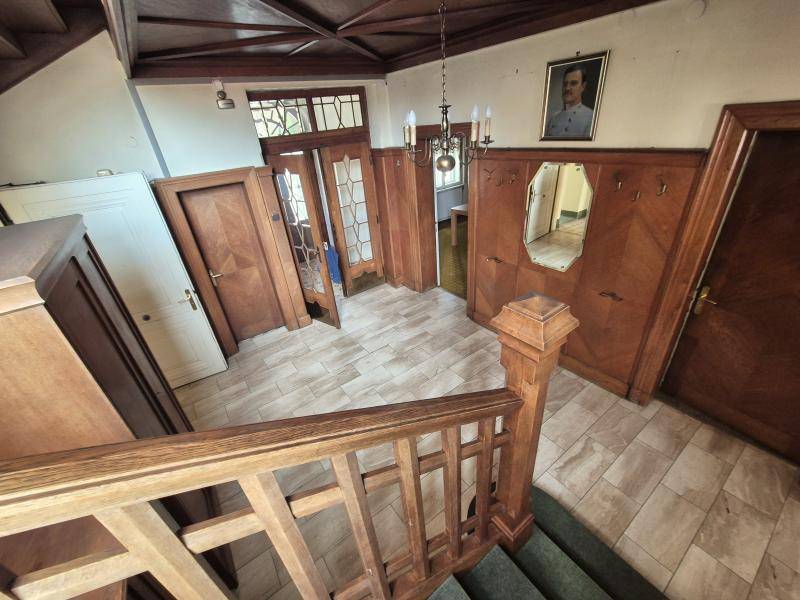 Geräumiger Eingangsbereich mit Fliesenboden, Holzvertäfelung und einer Holztreppe.