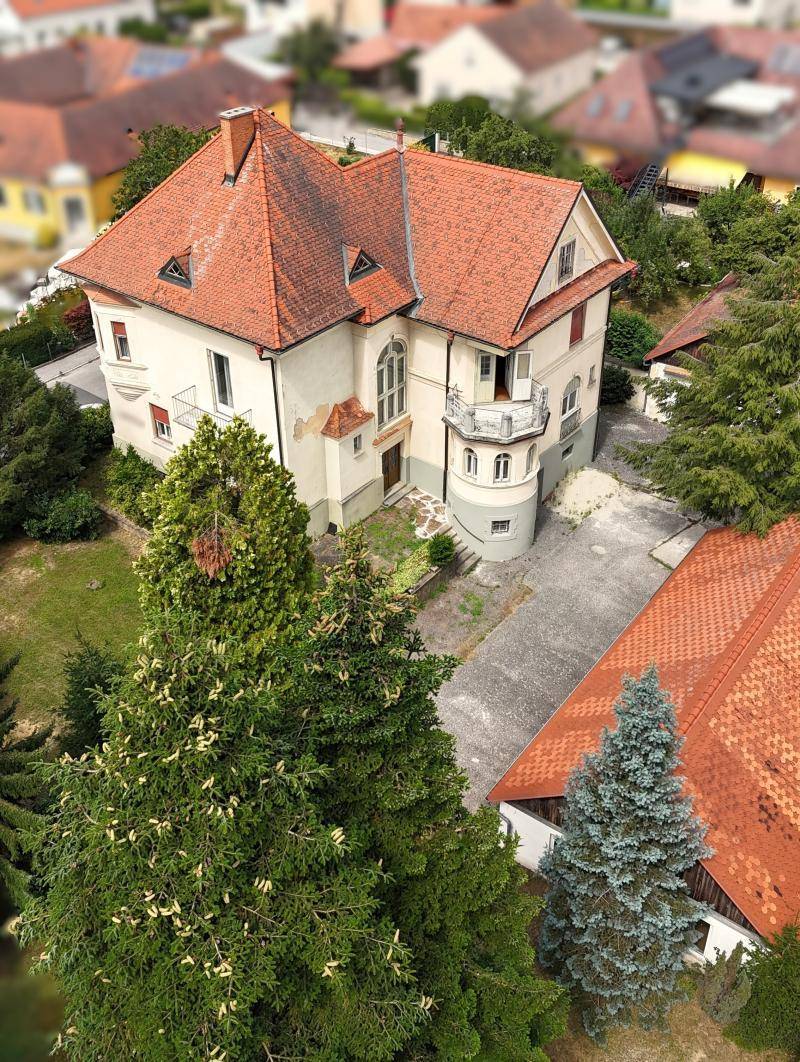 Historische Villa mit großem Grundstück und Nebengebäuden, umgeben von altem Baumbestand.