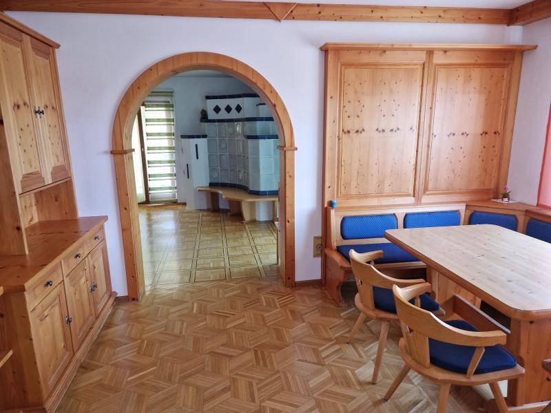 Traditioneller Essbereich mit Holzboden, Einbaumöbeln und Durchgang zum Kachelofen.