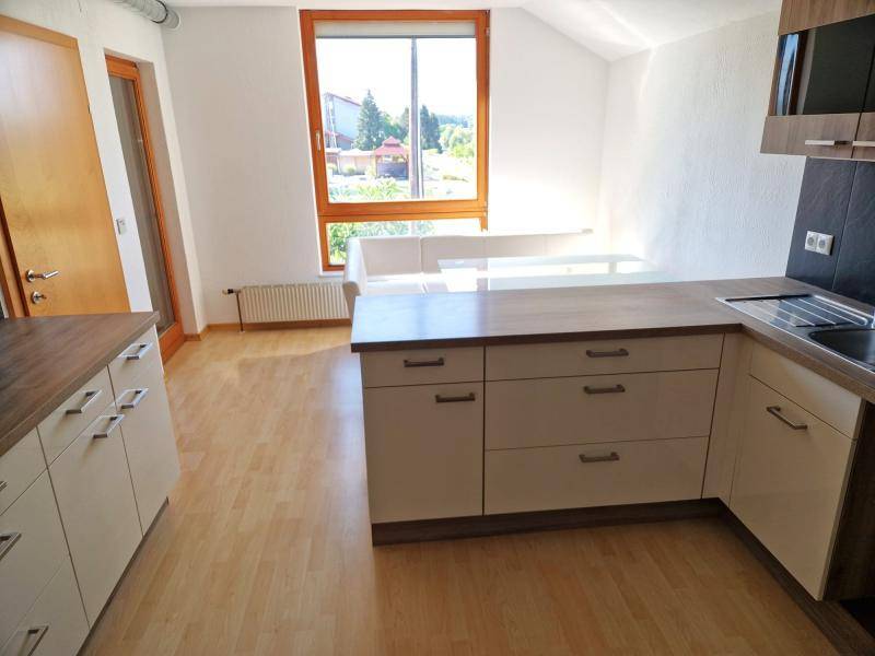 Offene Küchenzeile mit Holztheke, Einbauschränken und Blick aus dem Fenster.