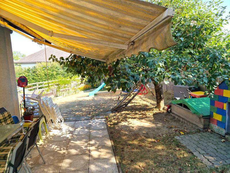 Sonniger Gartenbereich mit Markise, Sitzgelegenheiten und Spielgeräten für Kinder.