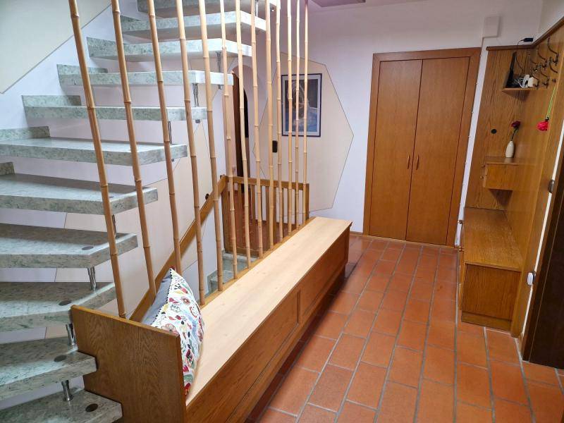 Heller Eingangsbereich mit Granittreppe, Holzbank und Garderobe, die zu den oberen Etagen führt.