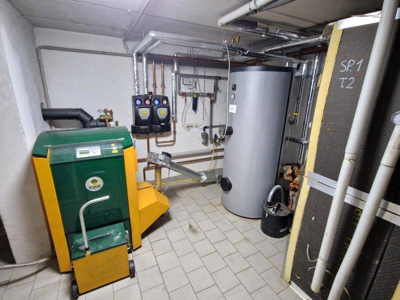 Heizungsraum im Keller mit moderner Pelletheizung und Warmwasserspeicher.