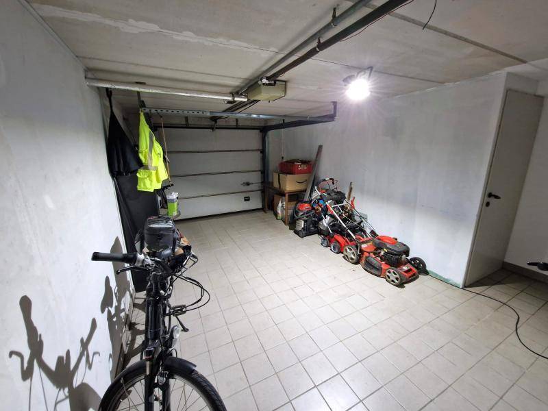 Geräumige Garage mit Fliesenboden, Abstellfläche und Garagentor.
