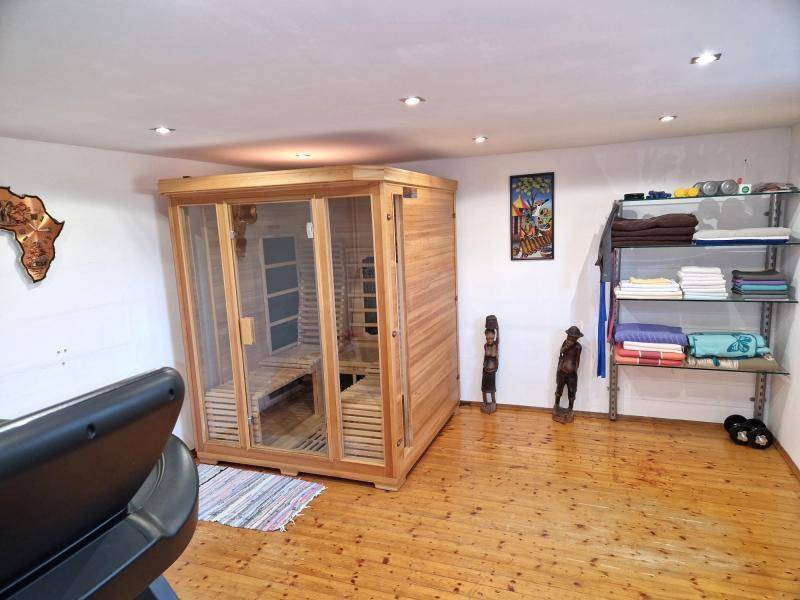 Geräumiger Wellnessbereich mit moderner Holzsauna und Fitnessgeräten auf Holzboden.
