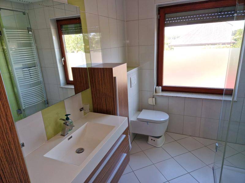 Modernes Badezimmer mit Dusche, Waschtisch und Fenster für Tageslicht.