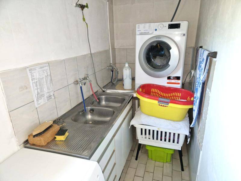 Praktischer Waschraum mit Doppelwaschbecken, Waschmaschine und Fliesenboden.