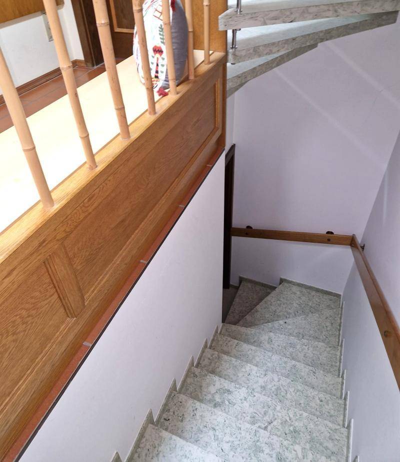 Detailansicht einer Granittreppe mit Holzgeländer, die in das Untergeschoss führt.