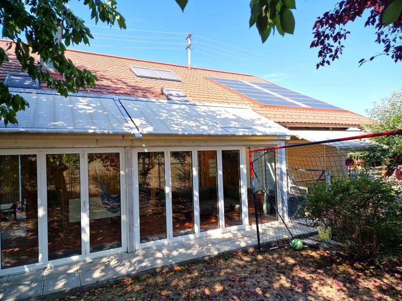 Rückansicht des Hauses mit Solaranlage auf dem Dach und verglastem Wintergarten.