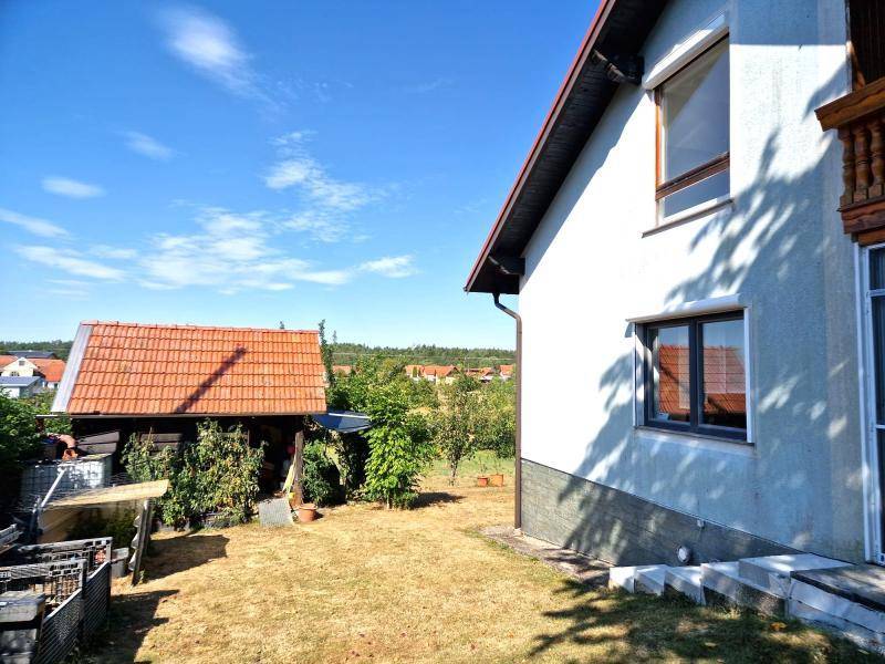 Seitenansicht des Hauses mit Gartenbereich, Obstbäumen und Blick in die Landschaft.