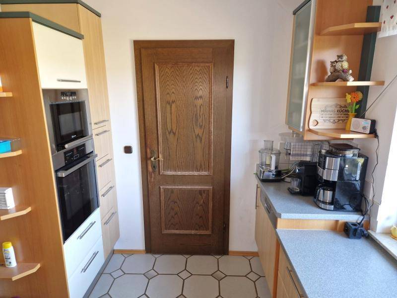 Kompakte Küche mit Einbaugeräten, Holzfronten und traditioneller Holztür.