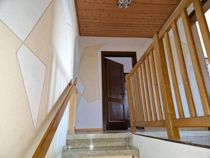 Treppenhaus mit Holzgeländer, Steinstufen und dekorativer Wandgestaltung.