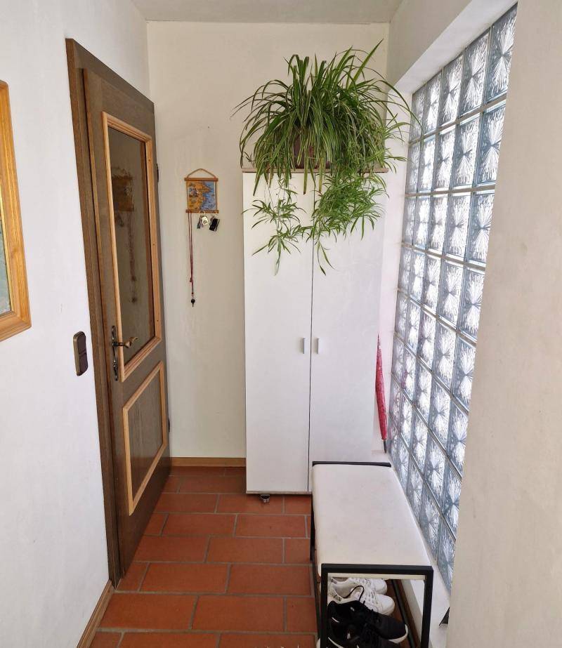 Eingangsbereich mit Terrakotta-Fliesen, Schuhbank und Glasbausteinwand.