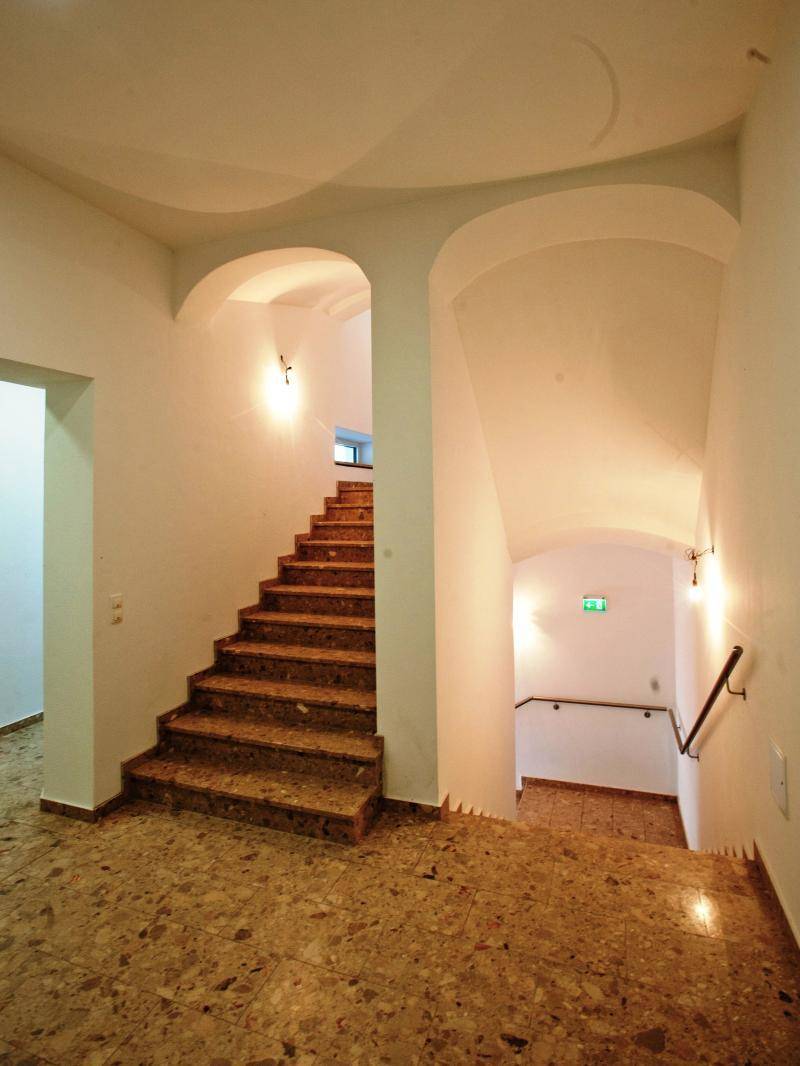 Helles Treppenhaus mit gewölbten Decken und Terrazzoboden in einem Altbau.