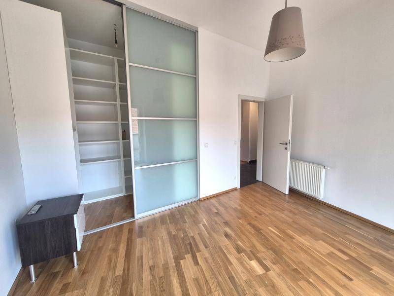 Schlafzimmer mit Holzboden, weißen Wänden und einem großen Einbauschrank mit Glasschiebetüren.