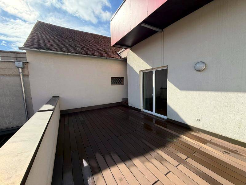 Terrasse mit dunklem Holzdeck und Zugang durch eine Glasschiebetür zum Innenbereich des Gebäudes.