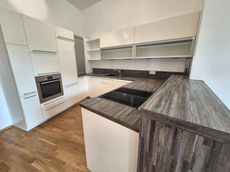 Moderne Küche mit weißen Schränken, integriertem Backofen und einer Kochinsel mit Induktionskochfeld.