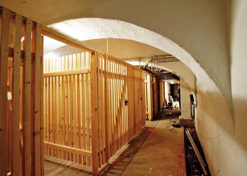 Kellerbereich mit Holzverschlägen für Lagerzwecke und gewölbter Decke.