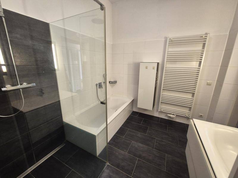 Modernes Badezimmer mit dunklen Fliesen, Badewanne, begehbarer Dusche und Handtuchheizkörper.