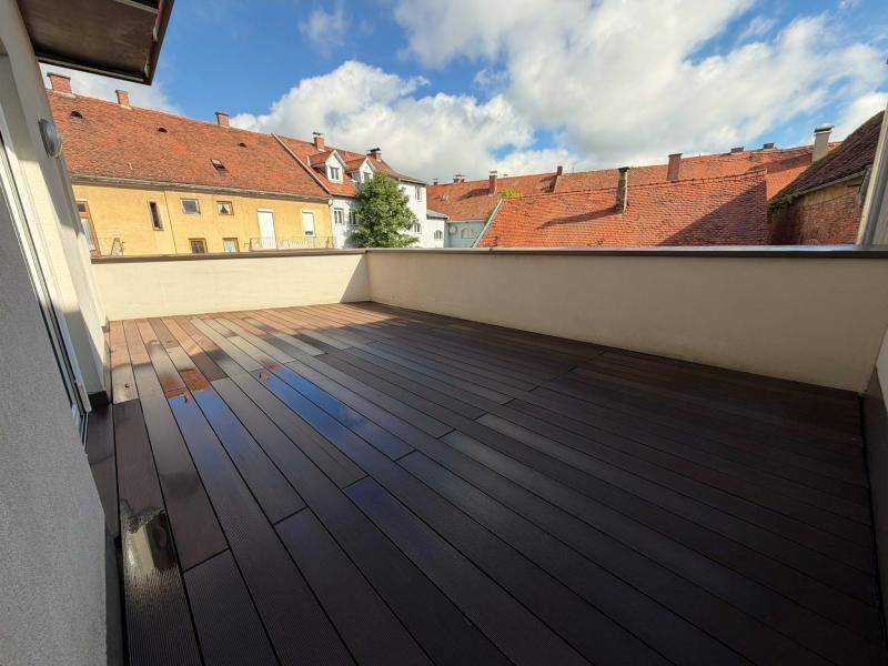 Weitläufige Außenterrasse mit modernem Holzdeck und malerischem Blick über die historischen Dächer.