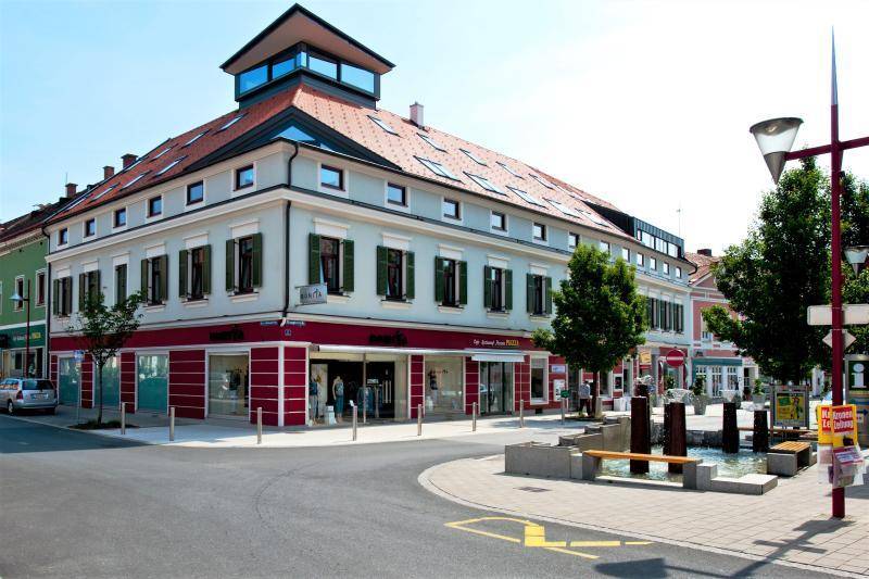 Städtisches Gebäude mit Geschäften im Erdgeschoss und Wohnungen darüber, an einer Straßenecke gelegen.