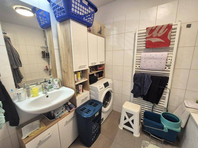 Praktisches Badezimmer mit Waschbecken, Waschmaschine und beheiztem Handtuchhalter.