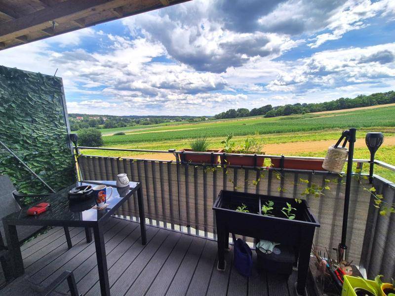 Balkon mit Sitzgelegenheiten und weitem Blick über die grüne Landschaft und Felder.