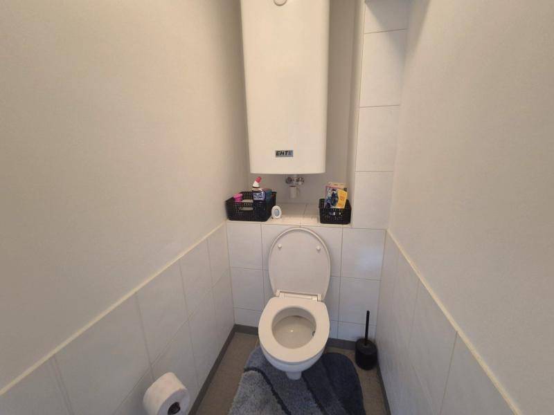 Separates WC mit Wandtoilette und hellen Fliesen, ideal für Gäste.