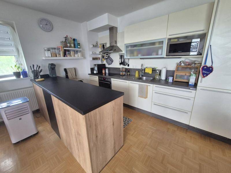 Moderne Küche mit Kücheninsel, hellen Schränken und integrierten Geräten für komfortables Kochen.
