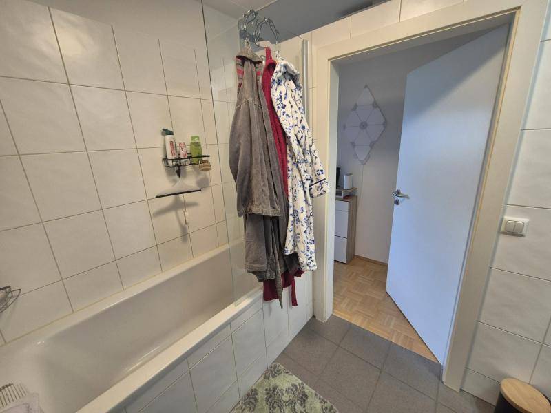 Badezimmer mit Badewanne und weißen Fliesen, bereit für die persönliche Gestaltung.
