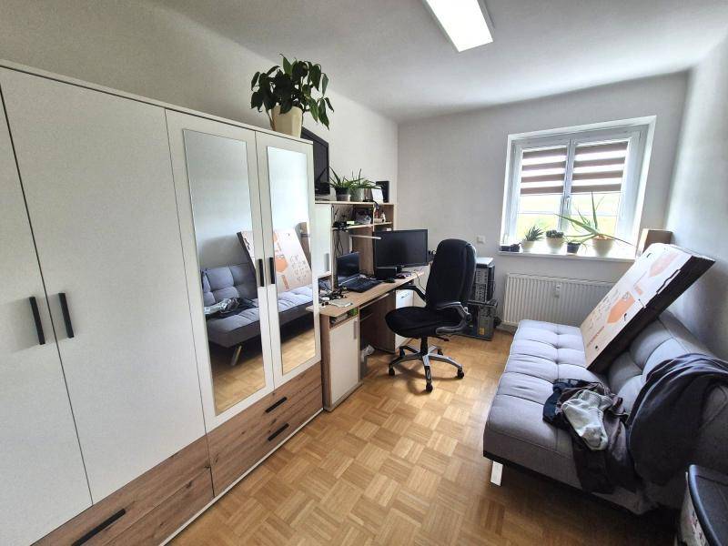 Vielseitiges Zimmer, eingerichtet als Büro mit Schreibtisch, Schrank und Schlafsofa.