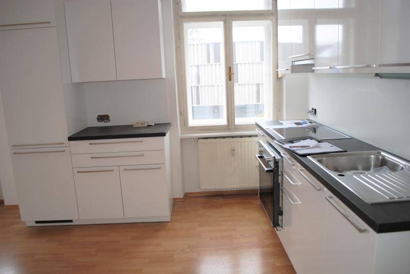 Detailansicht der Küche mit Spülbecken, Backofen und Fenster, das viel Tageslicht hereinlässt.