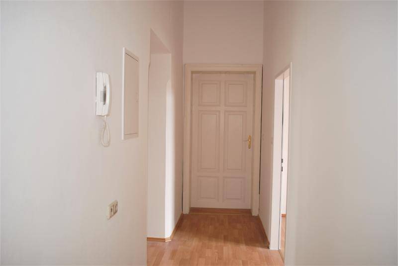 Flur mit geschlossener Tür am Ende und einer Gegensprechanlage an der Wand.
