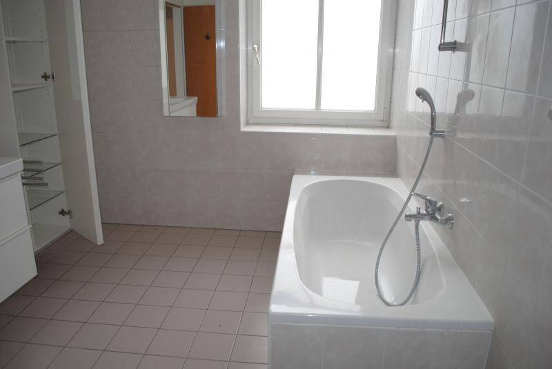 Badezimmer mit Badewanne, Duscharmatur und Fenster, das für natürliche Belüftung sorgt.