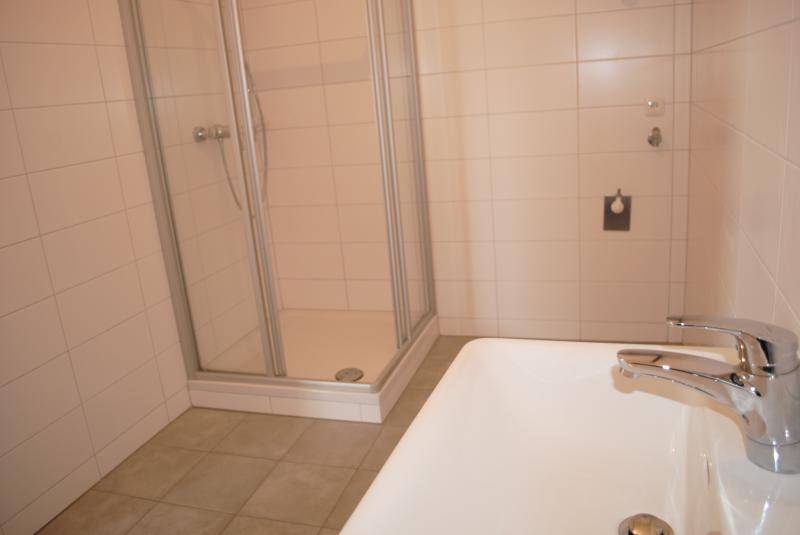 Modernes Badezimmer mit Duschkabine, Waschbecken und hellen Fliesen.