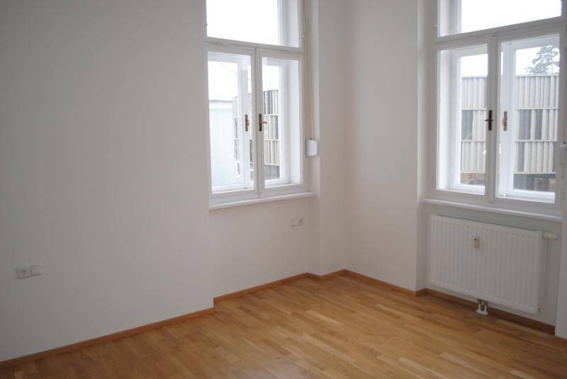 Lichtdurchfluteter Raum mit zwei großen Fenstern und hellem Parkettboden, bereit zum Einrichten.