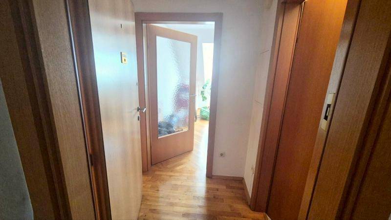 Heller Flur mit Holztüren, der zu verschiedenen Räumen der Wohnung führt.